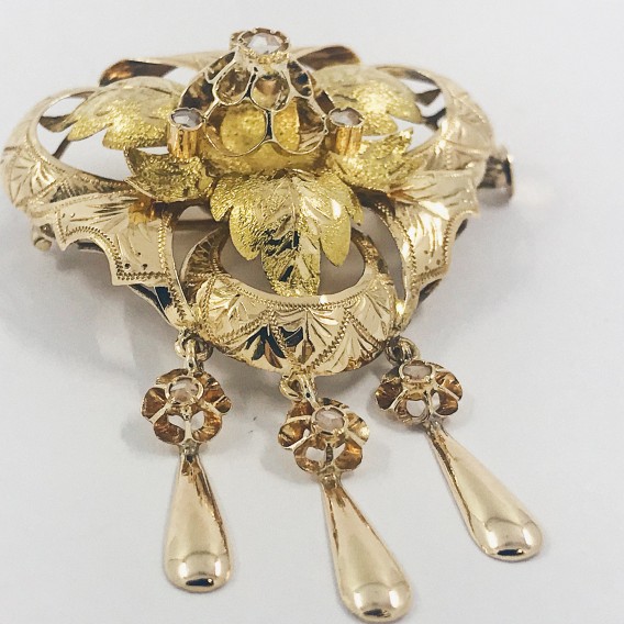 Broche triangular de oro con diamantes.