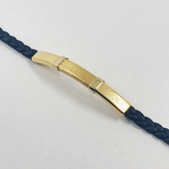 Pulsera con placa de oro y cuero trenzado.